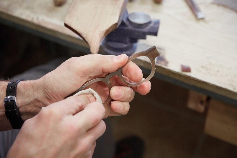Ein Handwerker feilt eine Brillenfassung aus Horn an der Werkbank nach